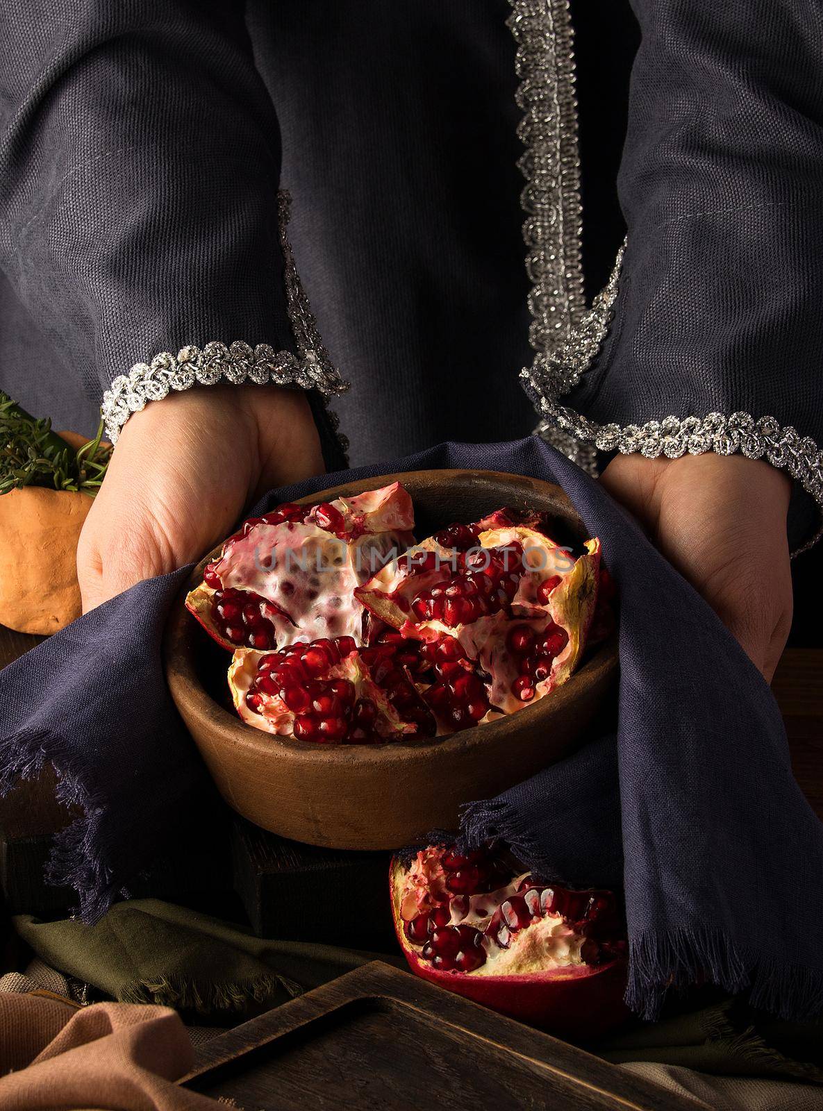 A vertical photo of woman's hands holding a bowl of pomegranate
