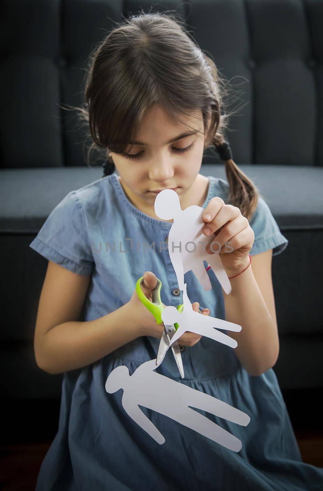 Child with a paper family in his hands. the concept of divorce, custody and child abuse. Selective focus. by yanadjana