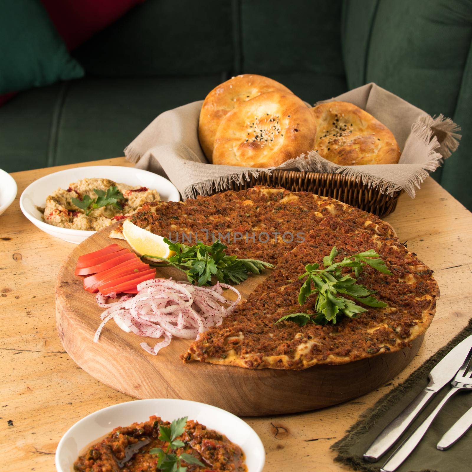 Close up shot of a lahmacun and a salad near basket of breads by A_Karim