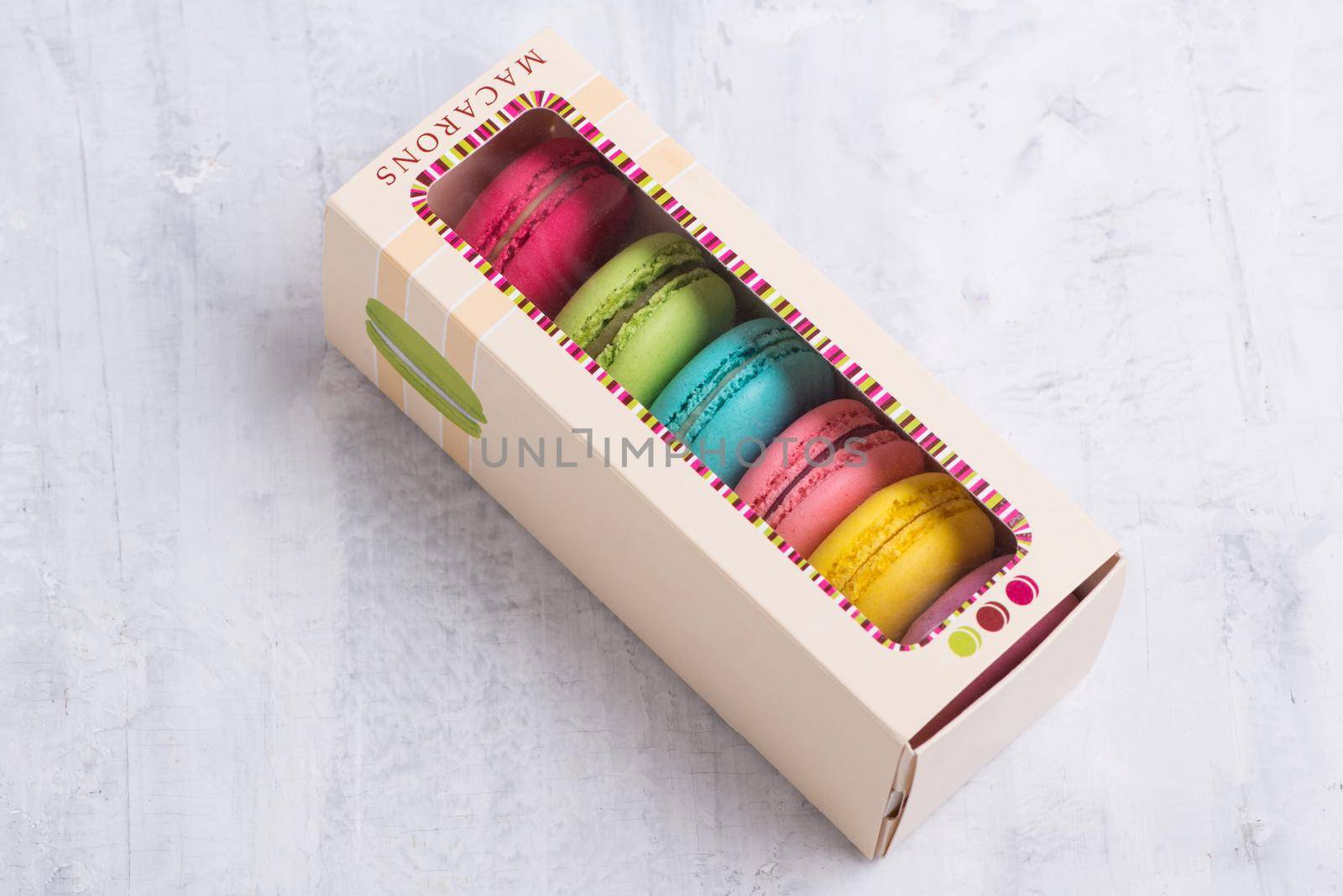 Angle shot of colorful French macarons placed in a cute box with a transparent top. by A_Karim