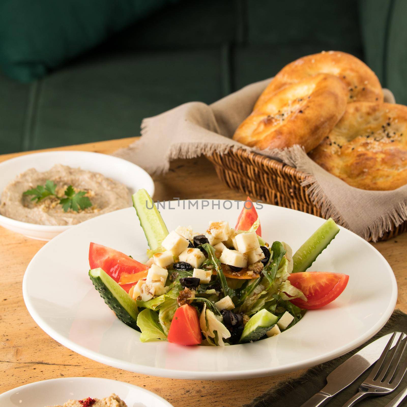 A close up shot of a salad and appetizers near basket of breads