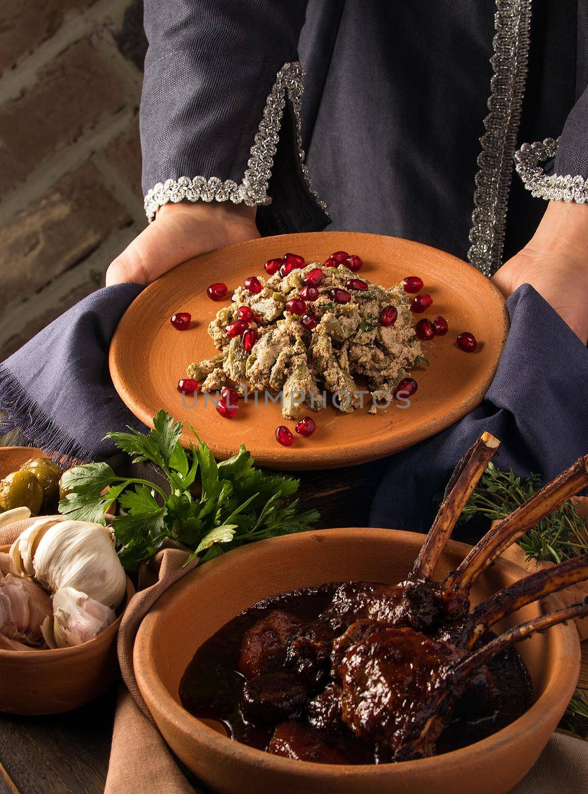 A vertical shot of a waitress presenting a kuchmachi and tomahawk steak in the background