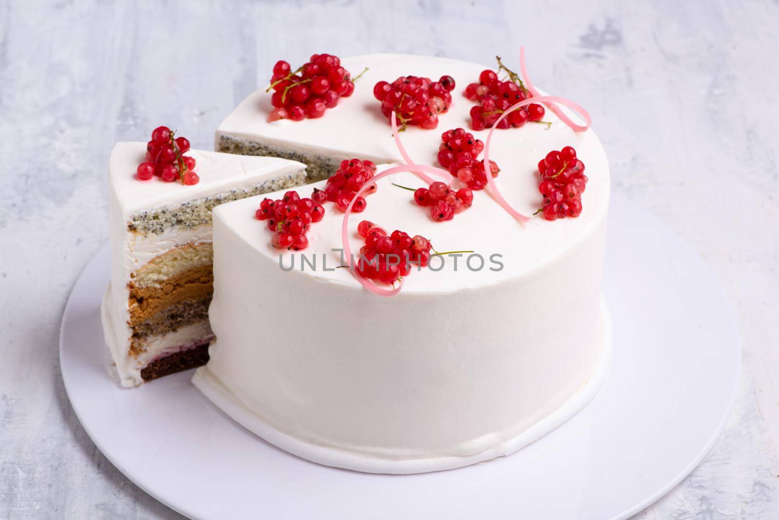 A top view shot of a white cake designed by red berry on a white plate