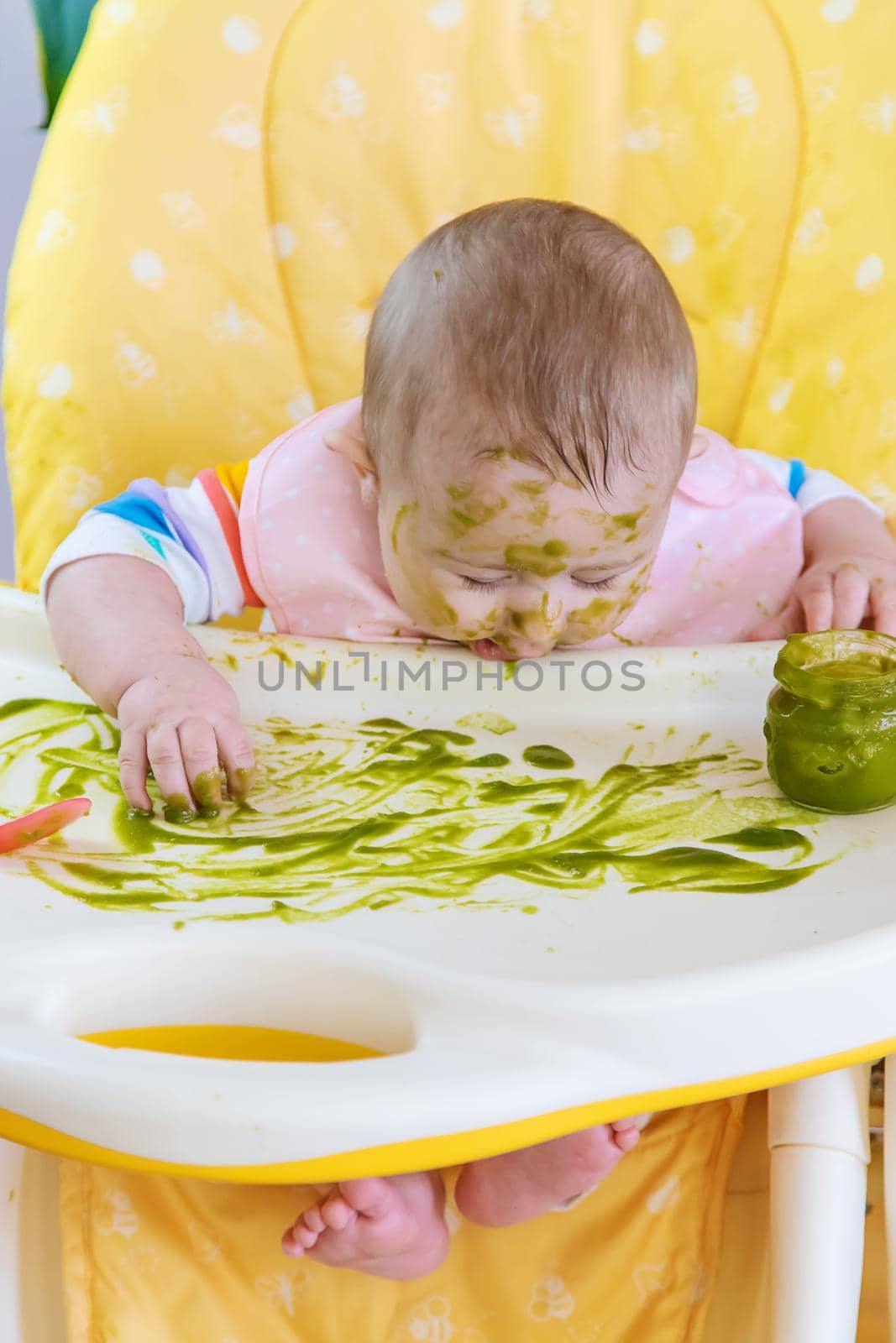 Little baby eats broccoli puree himself. Selective focus. People.
