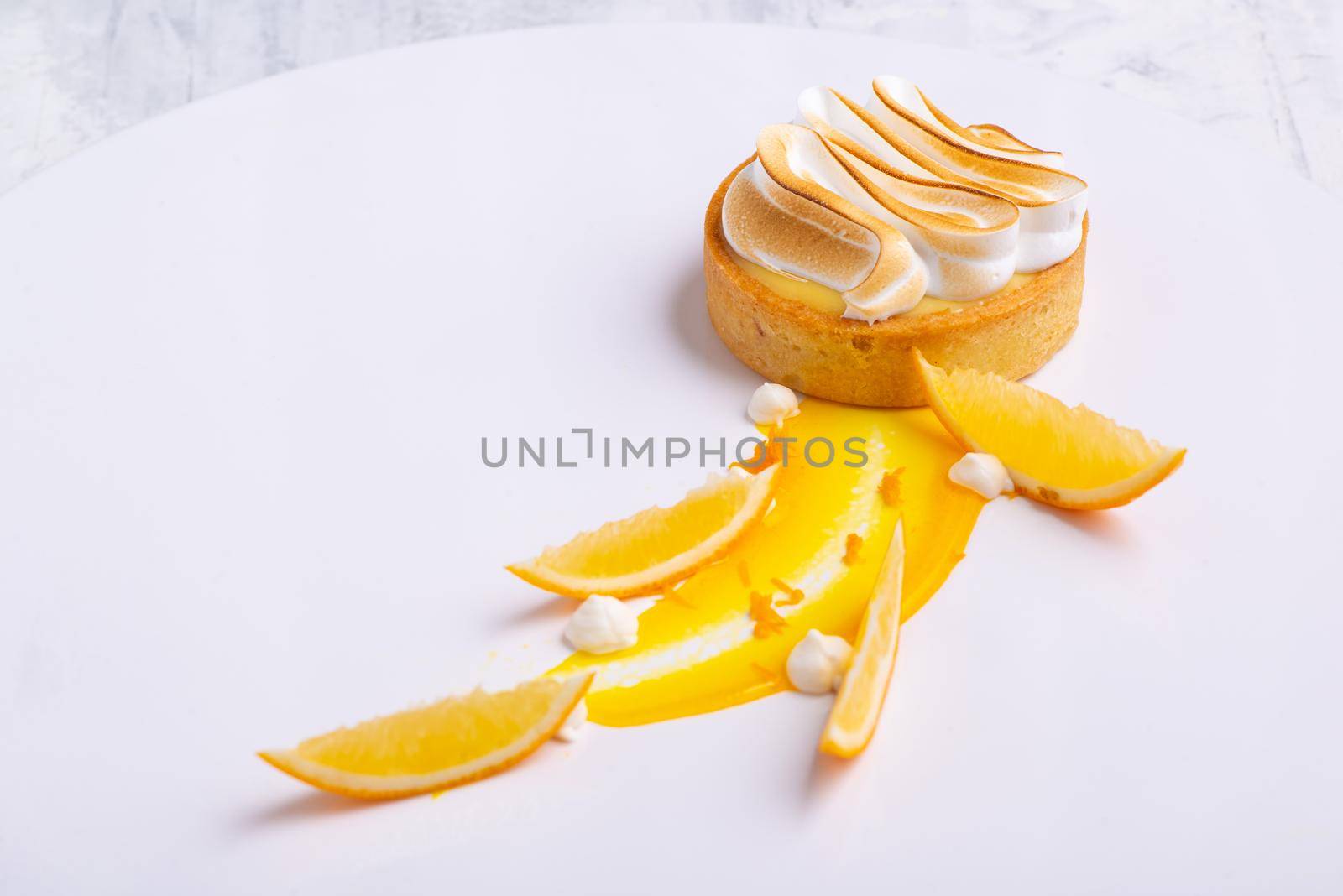 Appetizing lemon tartlets with meringue served on a white plate by A_Karim