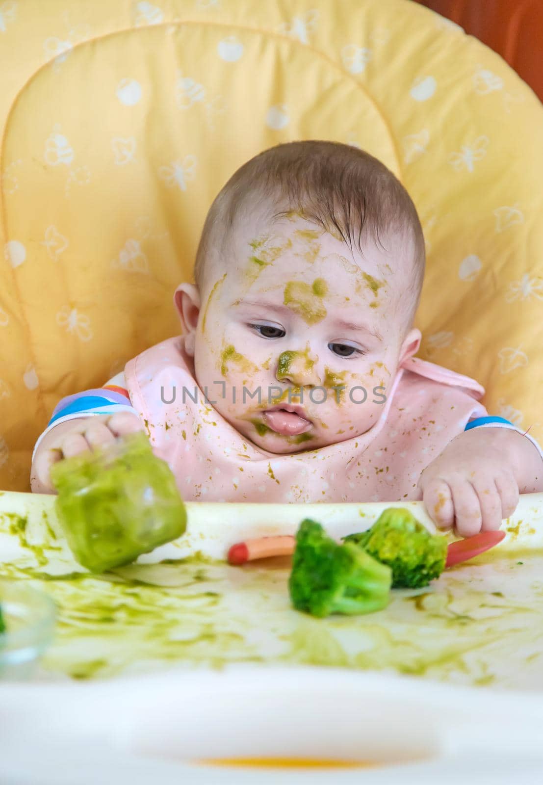 Little baby eats broccoli puree himself. Selective focus. People.