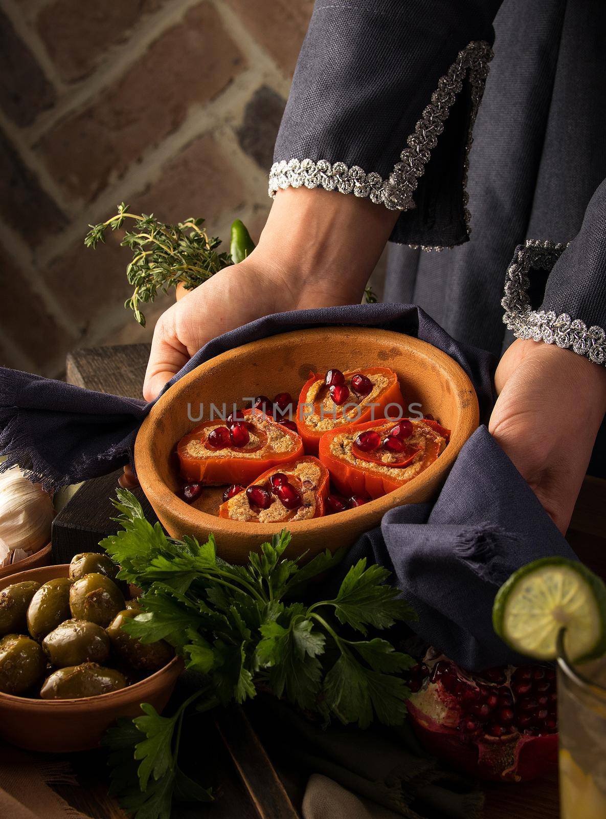 Vertical photo of woman's hands holding a plate of Baked pears with honey, walnuts and cranberries by A_Karim