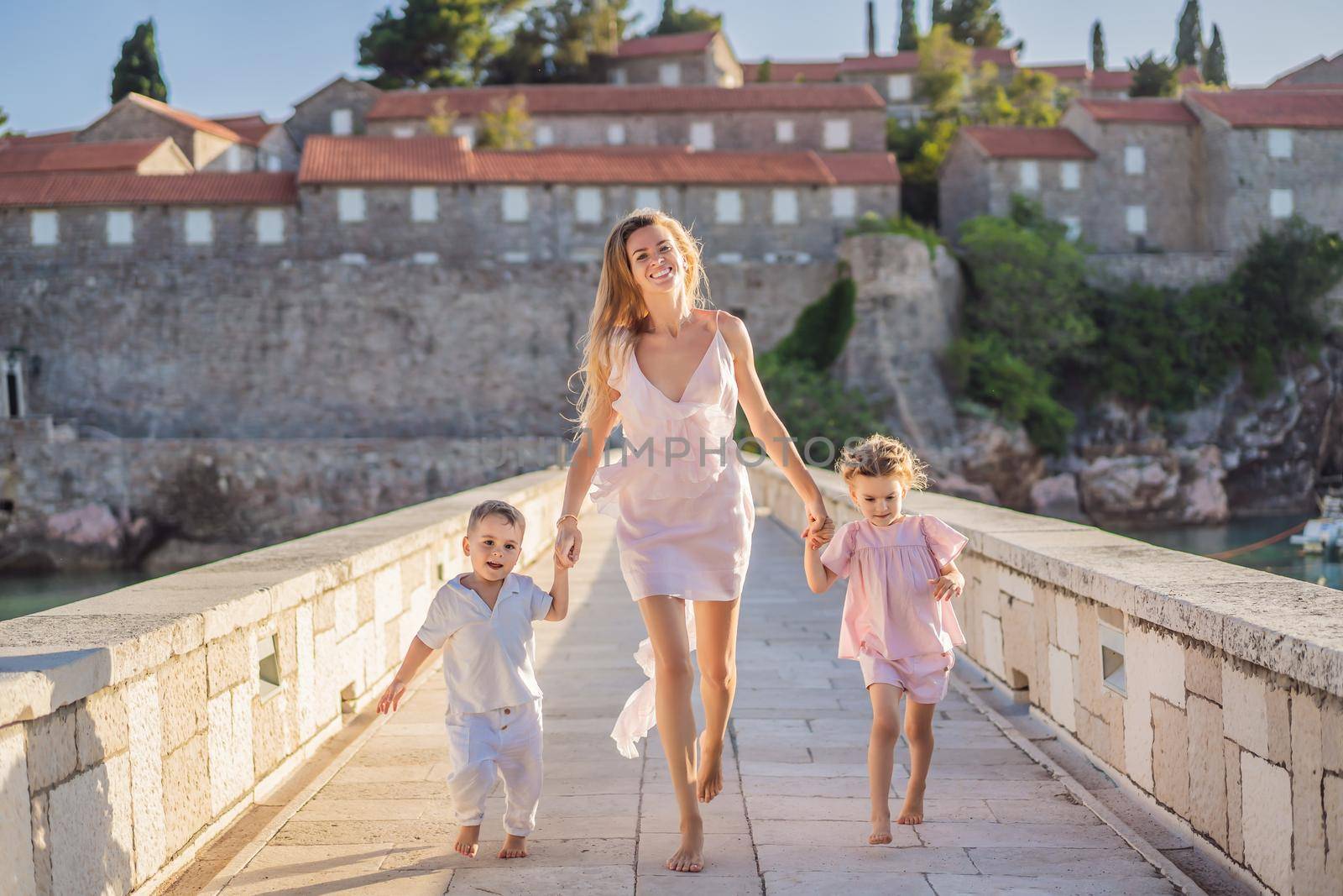 Mother and two children daughter and son tourists on background of beautiful view St. Stephen island, Sveti Stefan on the Budva Riviera, Budva, Montenegro. Travel to Montenegro concept.