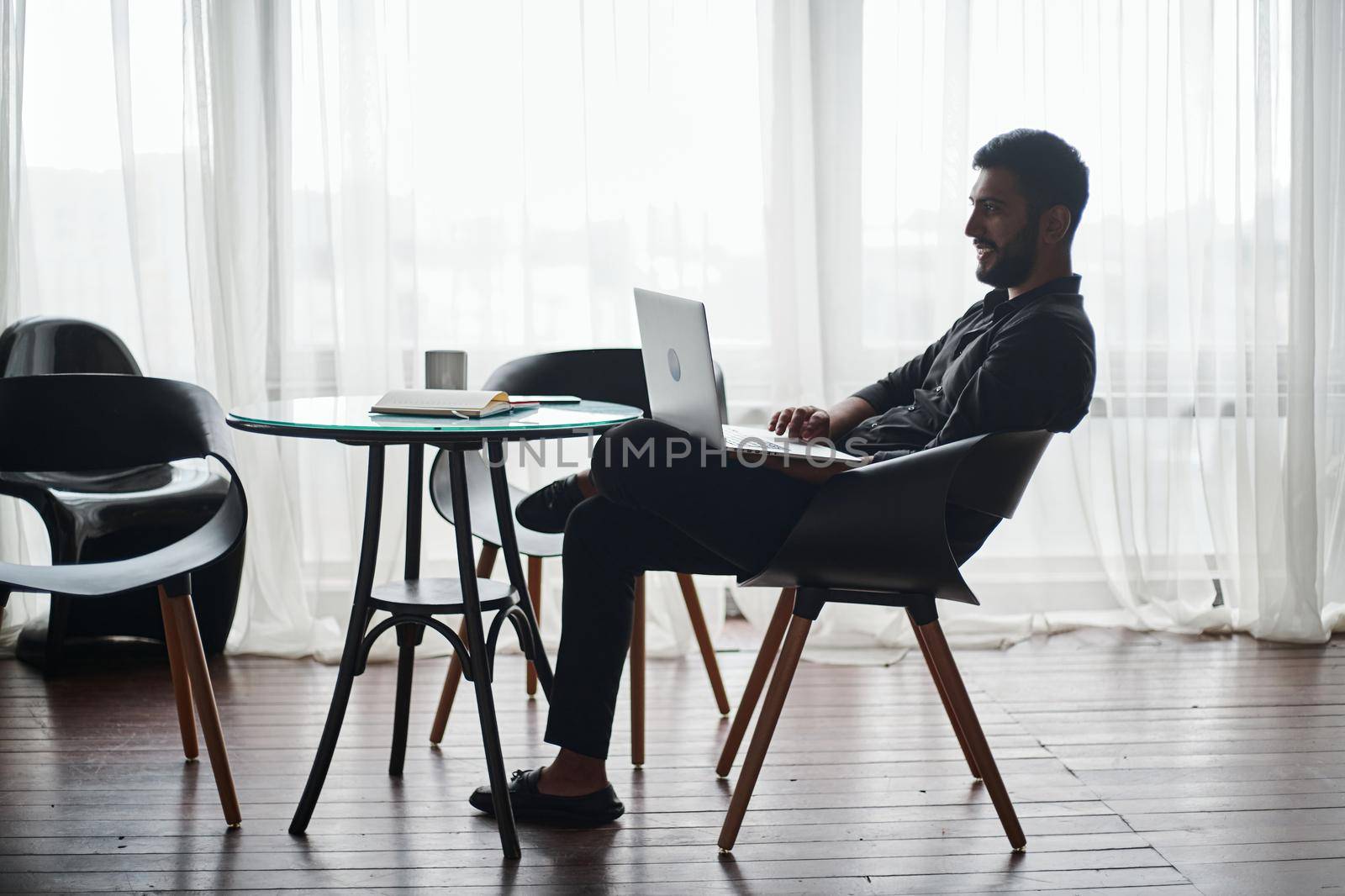 young business man working on a laptop while sitting at a coffee table. by SmartPhotoLab