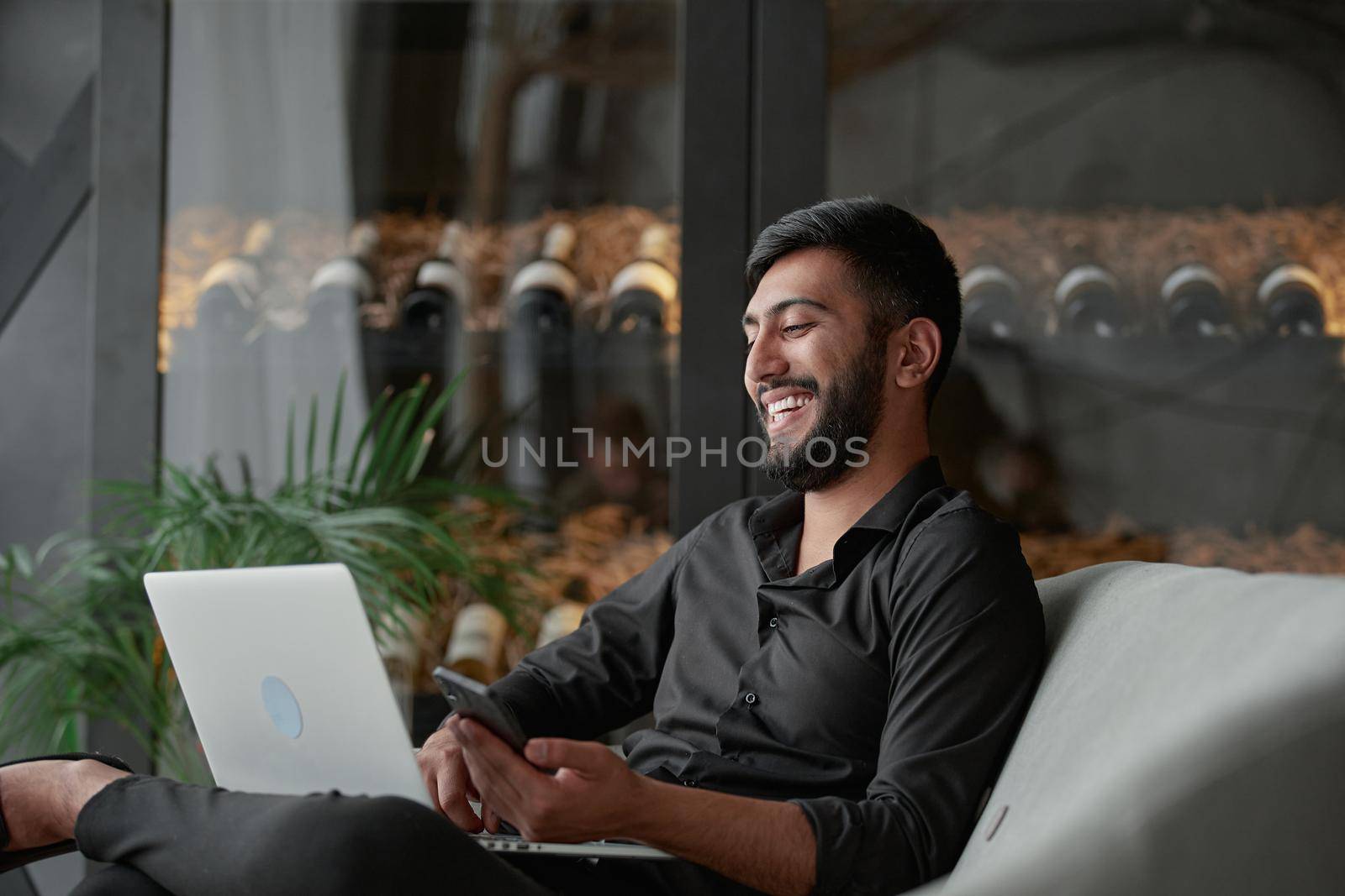 business man with a smartphone and laptop sitting in an armchair . by SmartPhotoLab