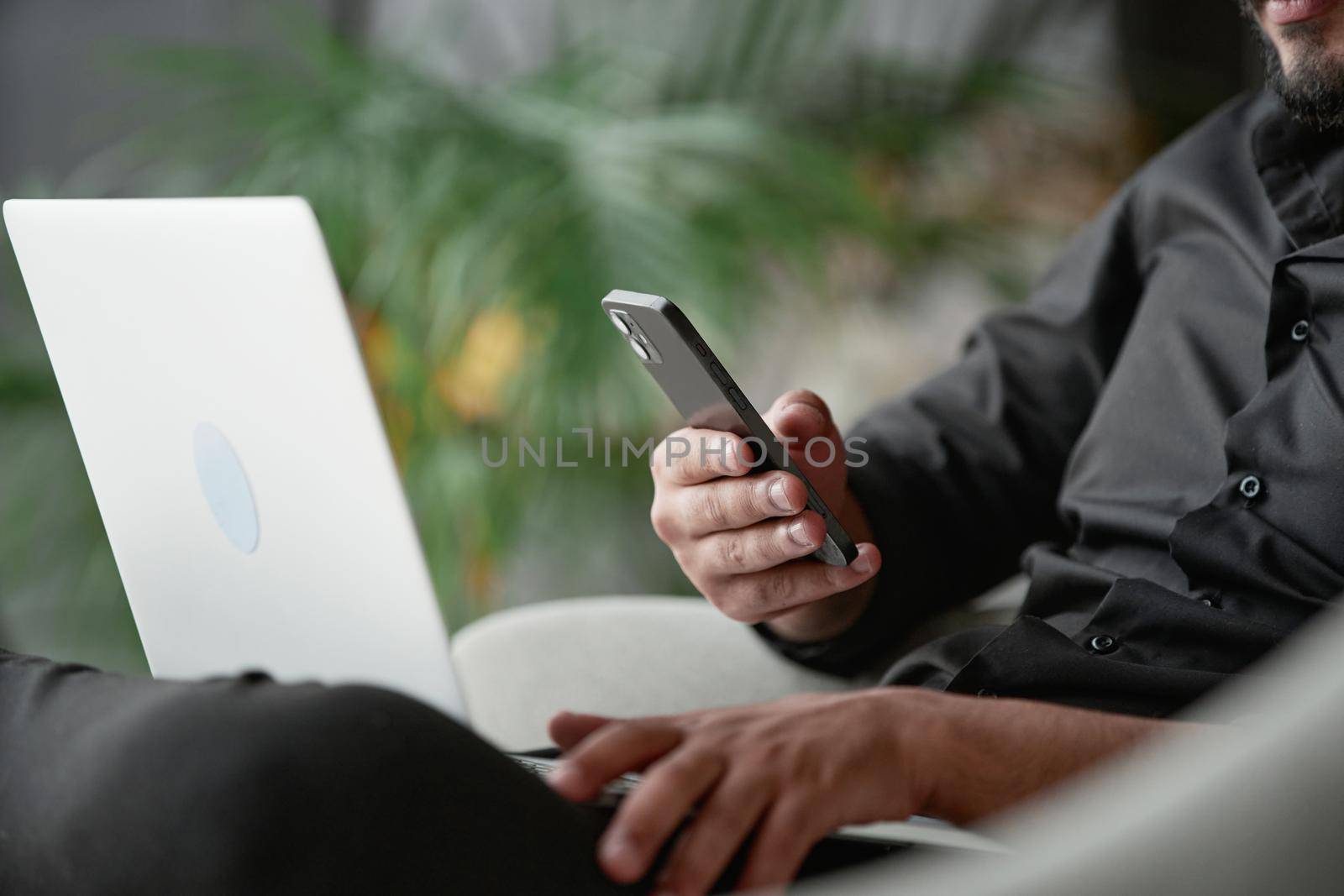 business man using a smartphone and a laptop at the same time. by SmartPhotoLab