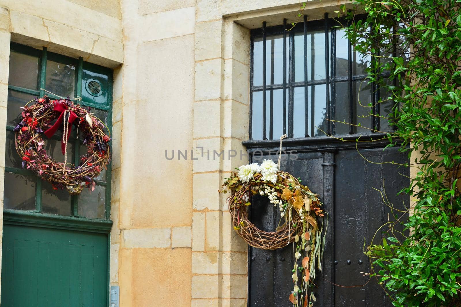 Wreaths with the red berries blackberry and the dry leaves hanging on a doors.
