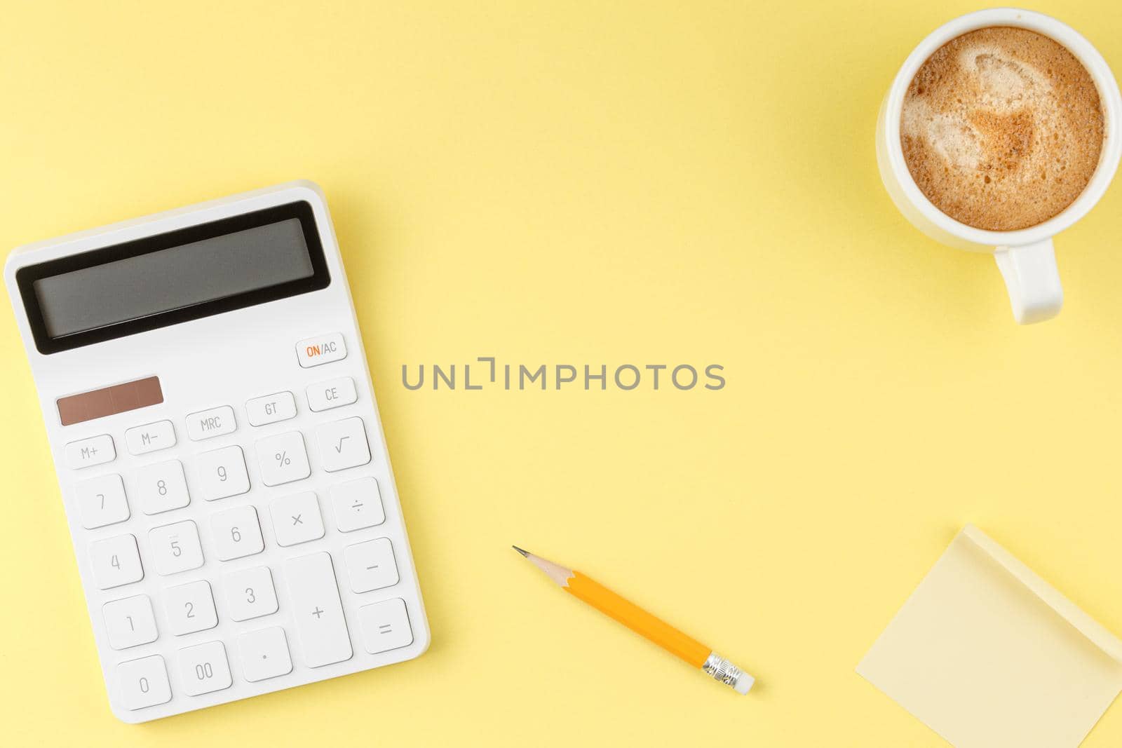 White calculator with coffee cup on yellow isolated background. Office Concept top view.