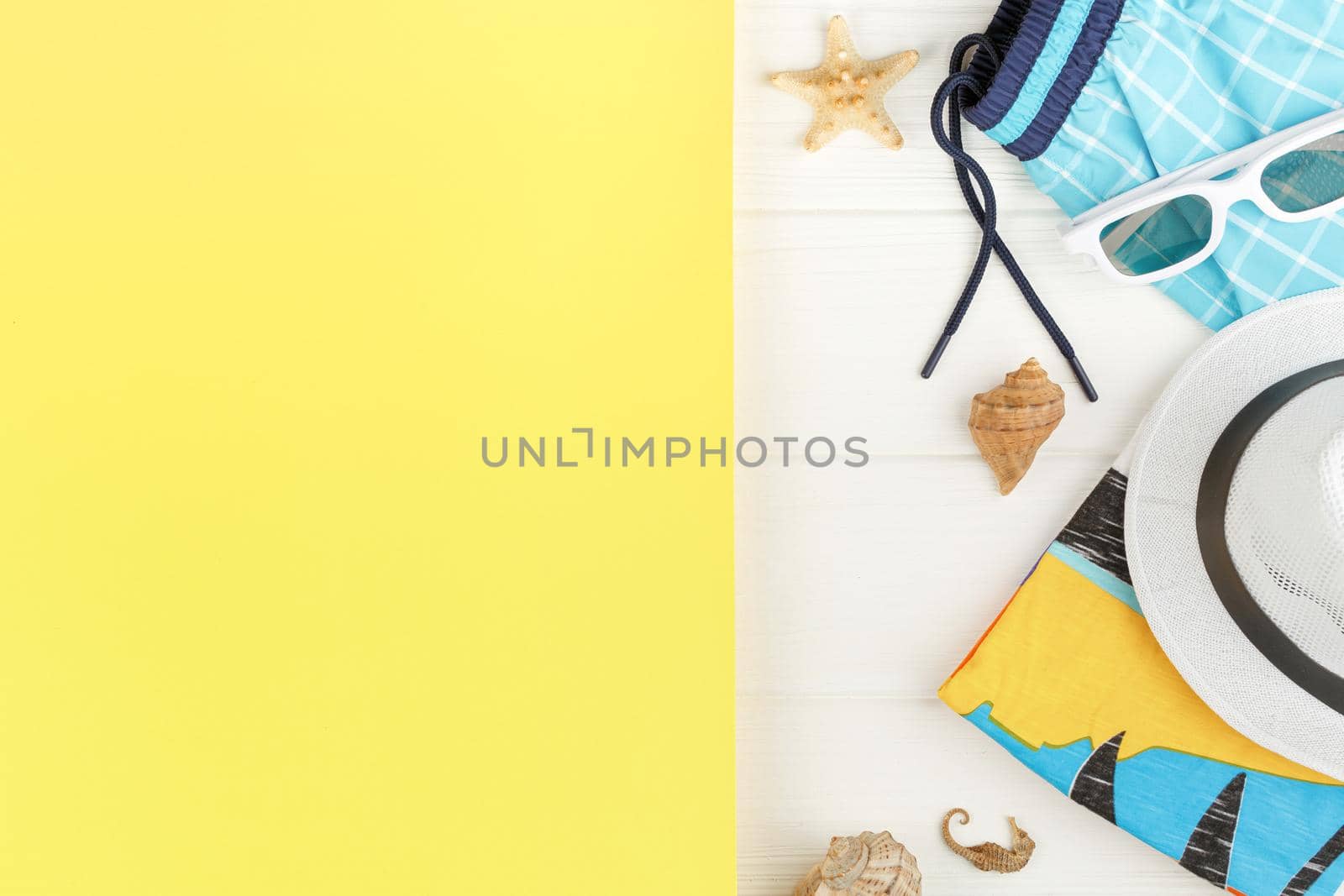 Beach clothes and sunglasses on white wooden background. Banner with yellow copy space. Summer vacation concept. Flat lay. Starfish and seashells decor.