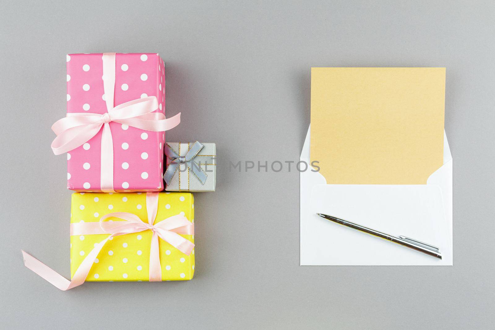 Presents in wrapping paper with polka dots on gray isolated background. Top view. Note sheet in an envelope with pen. Flat lay.