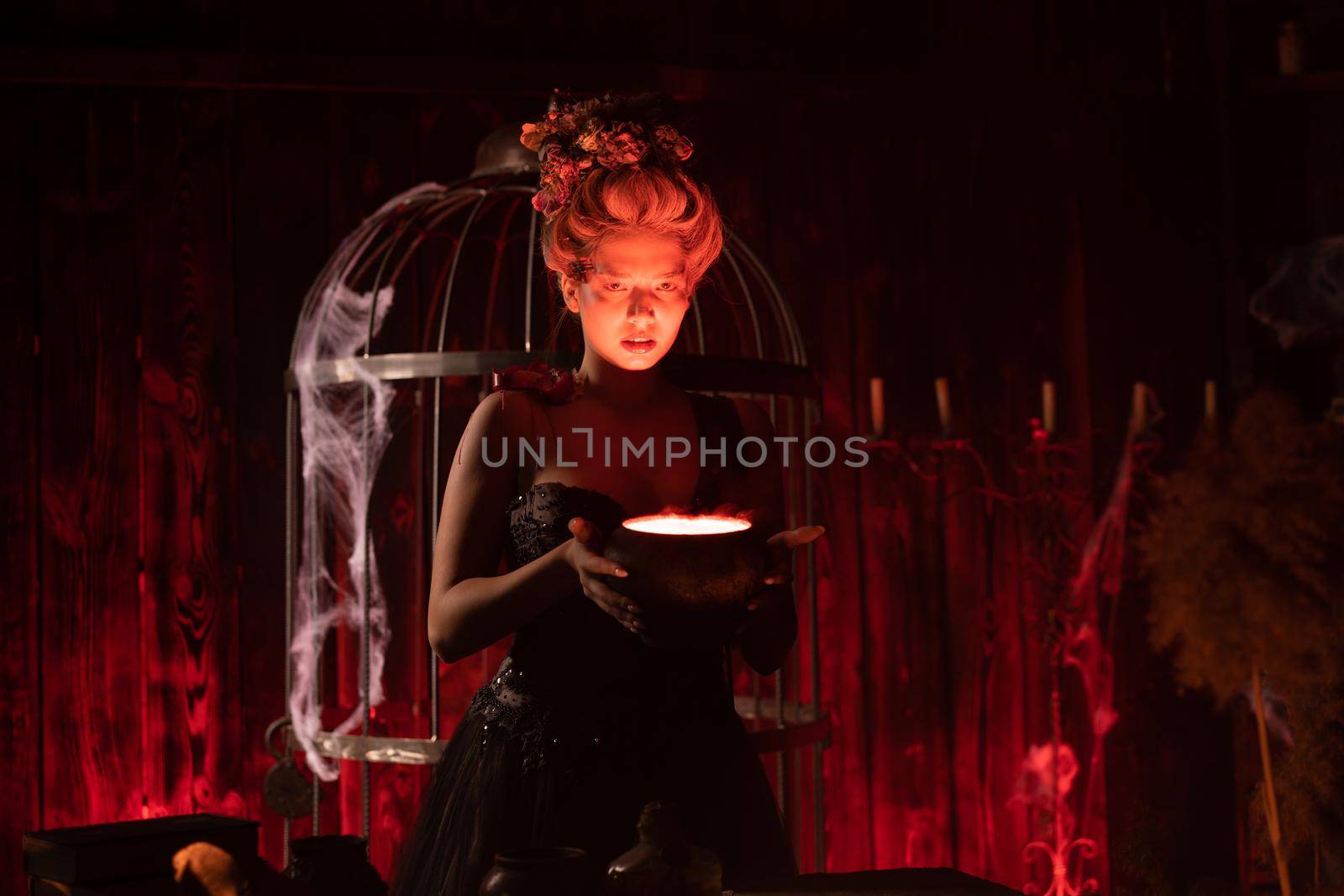 Halloween Witch with cauldron. Beautiful young woman conjuring, making witchcraft by andreonegin