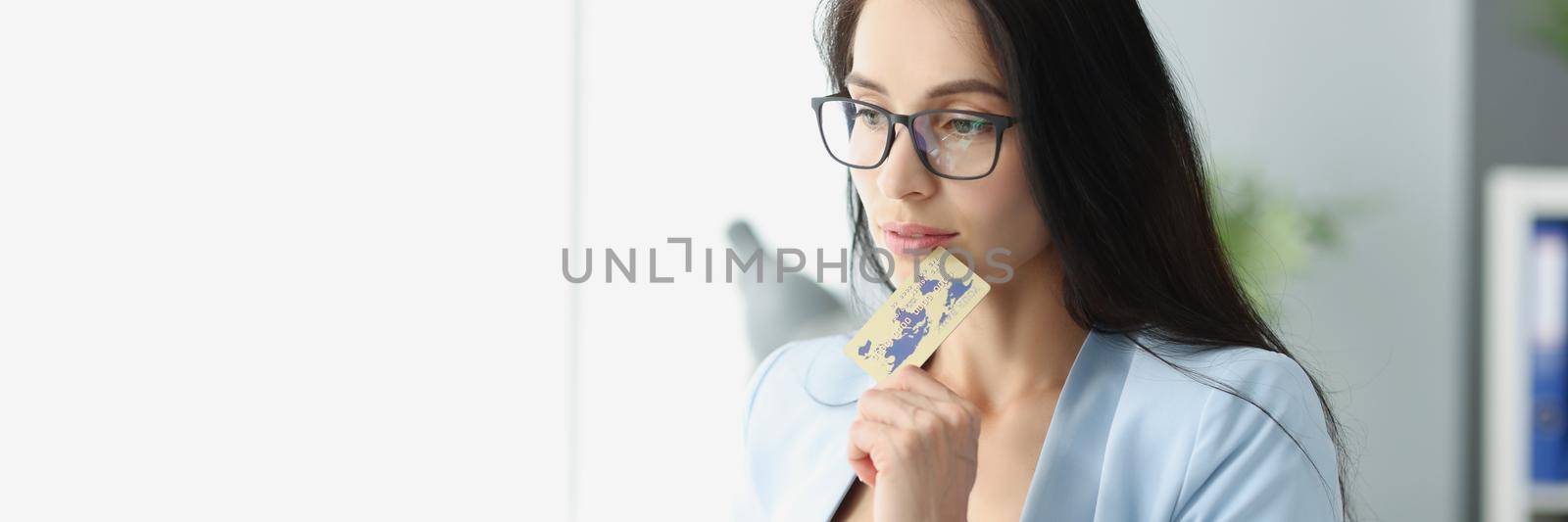 Portrait of brunette charming woman think how to spend money on credit card. Young female plan big shopping looking in window. Bank, finance, spend concept