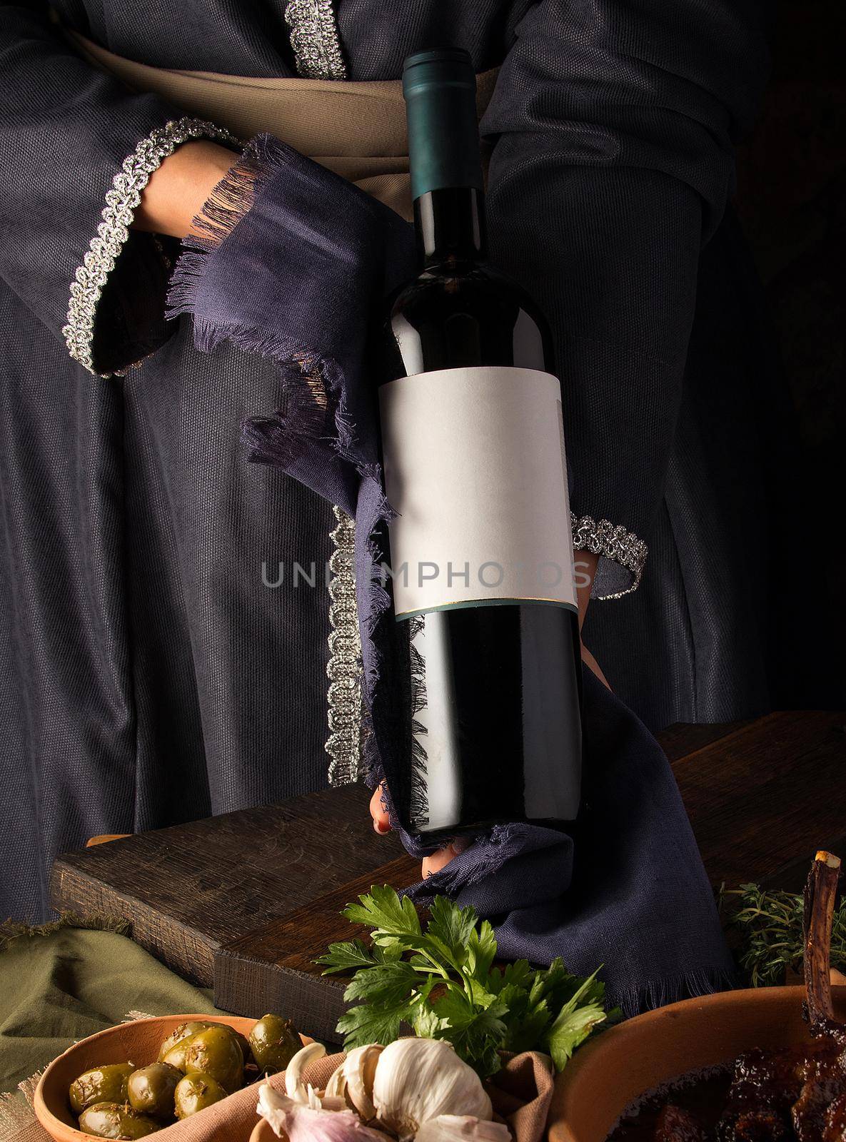 Vertical shot of a person in a traditional costume showing a wine bottle by A_Karim