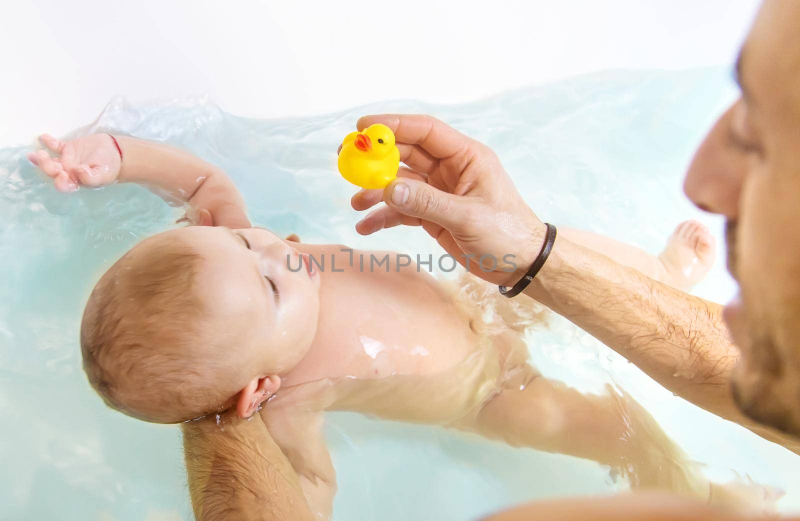 The father bathes the little baby. Selective focus. Copy space.