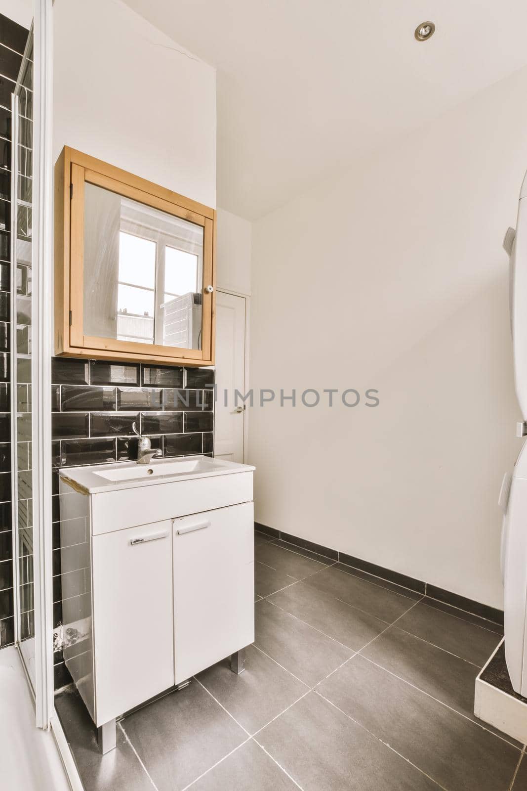 Fragment of interior of modern white bathroom with wooden cabinet under sink and with mirror