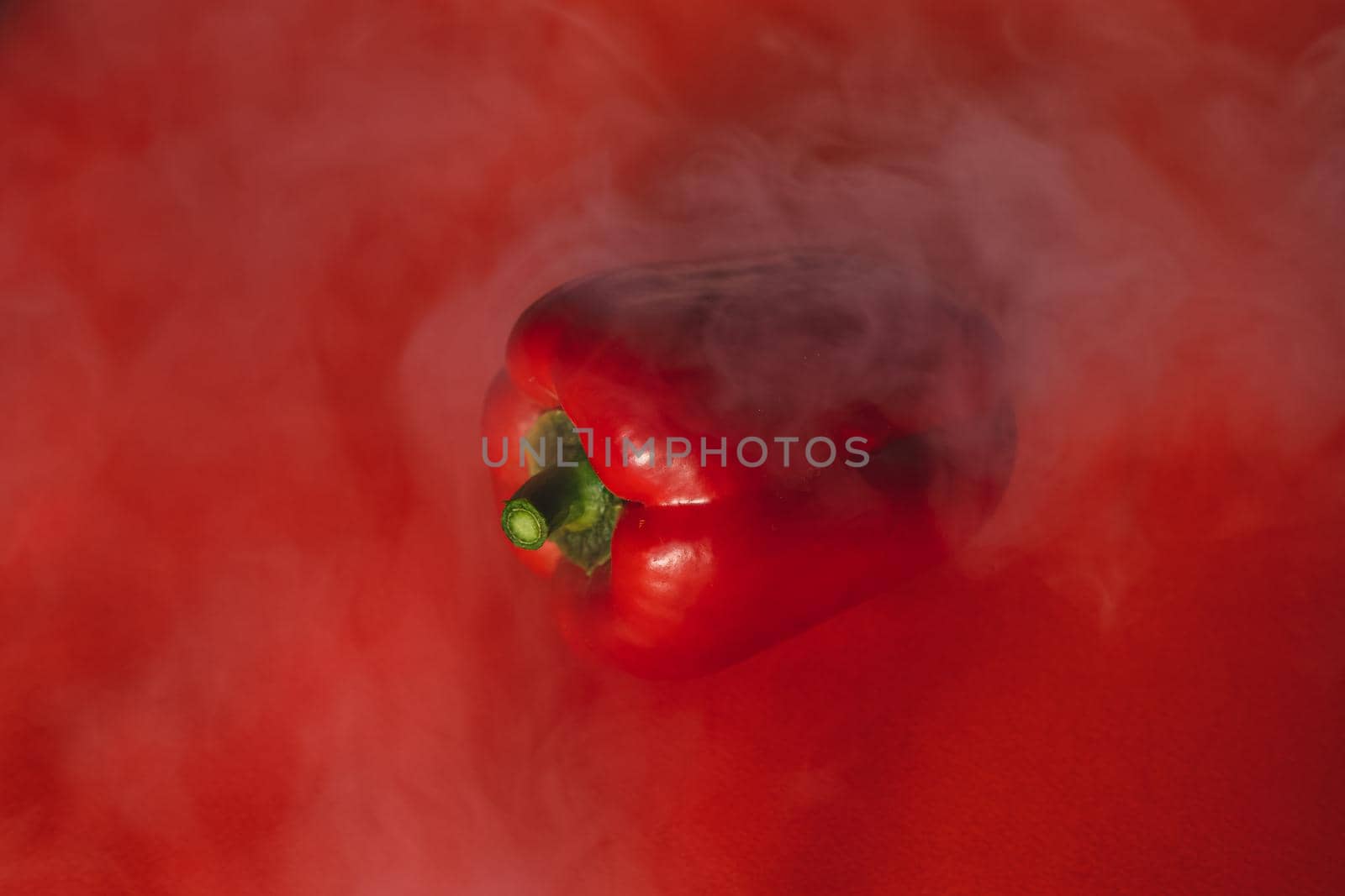 SWEET, fresh RED PEPPER ON A RED BACKGROUND WITH A LIGHT SMOKE.