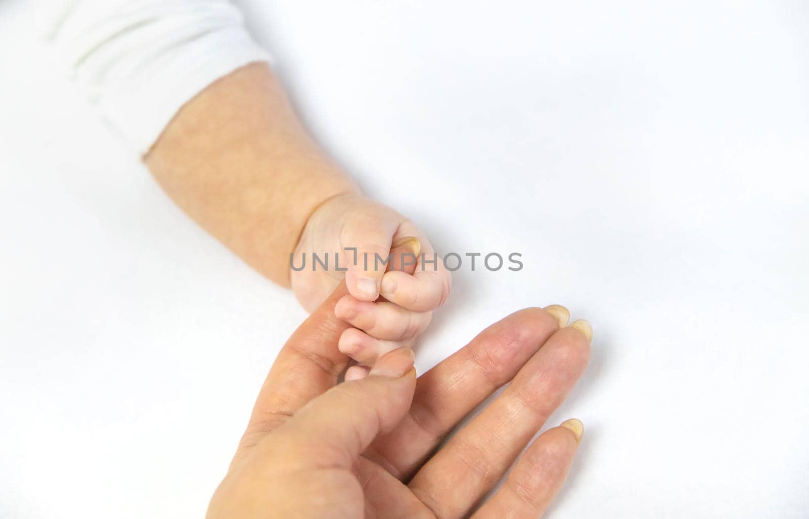 Baby hands with mom's hands against white background. Selective focus. People.