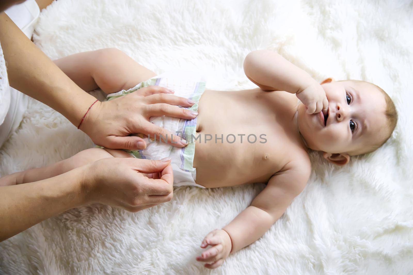 The mother is changing the baby's diaper. Selective focus. People.