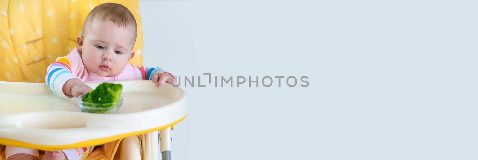 Little baby is eating broccoli vegetable puree. Selective focus. by yanadjana