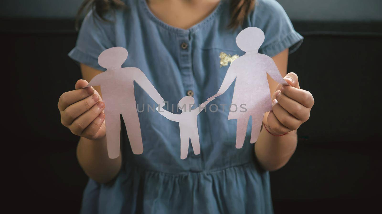 Child with a paper family in his hands. the concept of divorce, custody and child abuse. Selective focus. People.