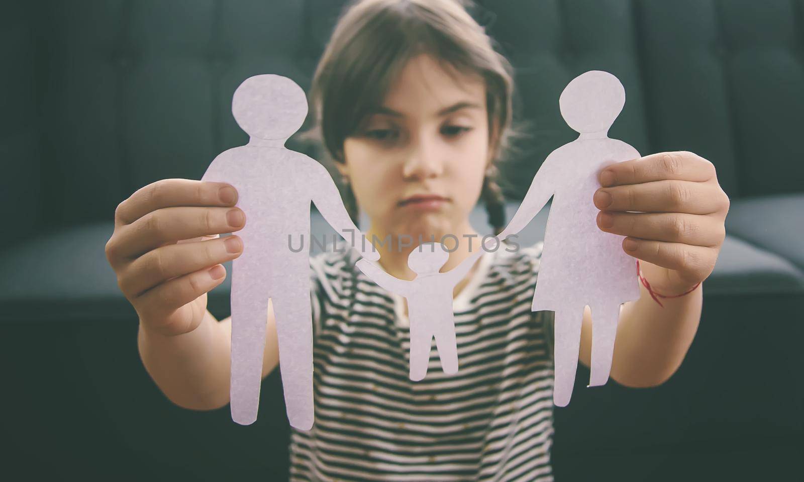 Child with a paper family in his hands. the concept of divorce, custody and child abuse. Selective focus. People.