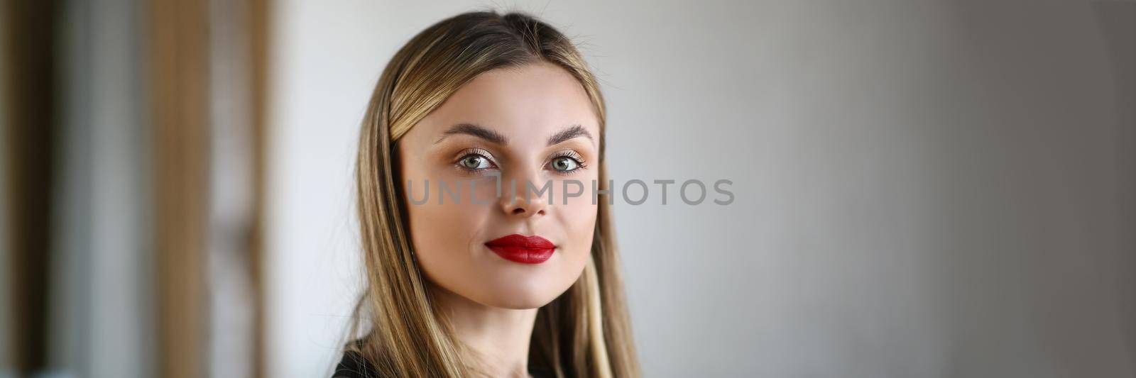 Portrait of beautiful young woman wearing bright makeup getting ready for party. Blonde woman applied red lipstick for impression. Beauty, modeling concept