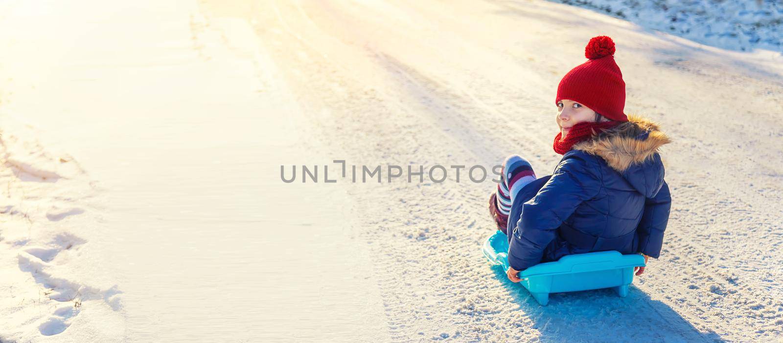 A child girl slides down a hill in the snow. Selective focus. by yanadjana