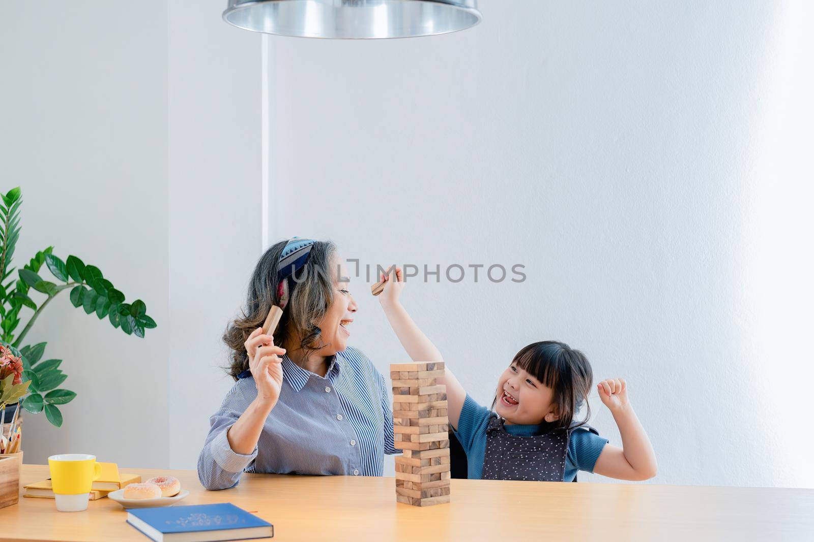 Asian portrait, grandchild granddaughter grandma grandmother and granddaughter happily join in activities to Block wood game Puzzle and enhance skills for grandchildren.