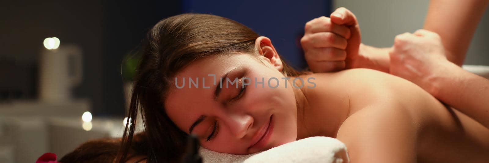 Relaxed smiling woman getting professional massage in spa centre by kuprevich