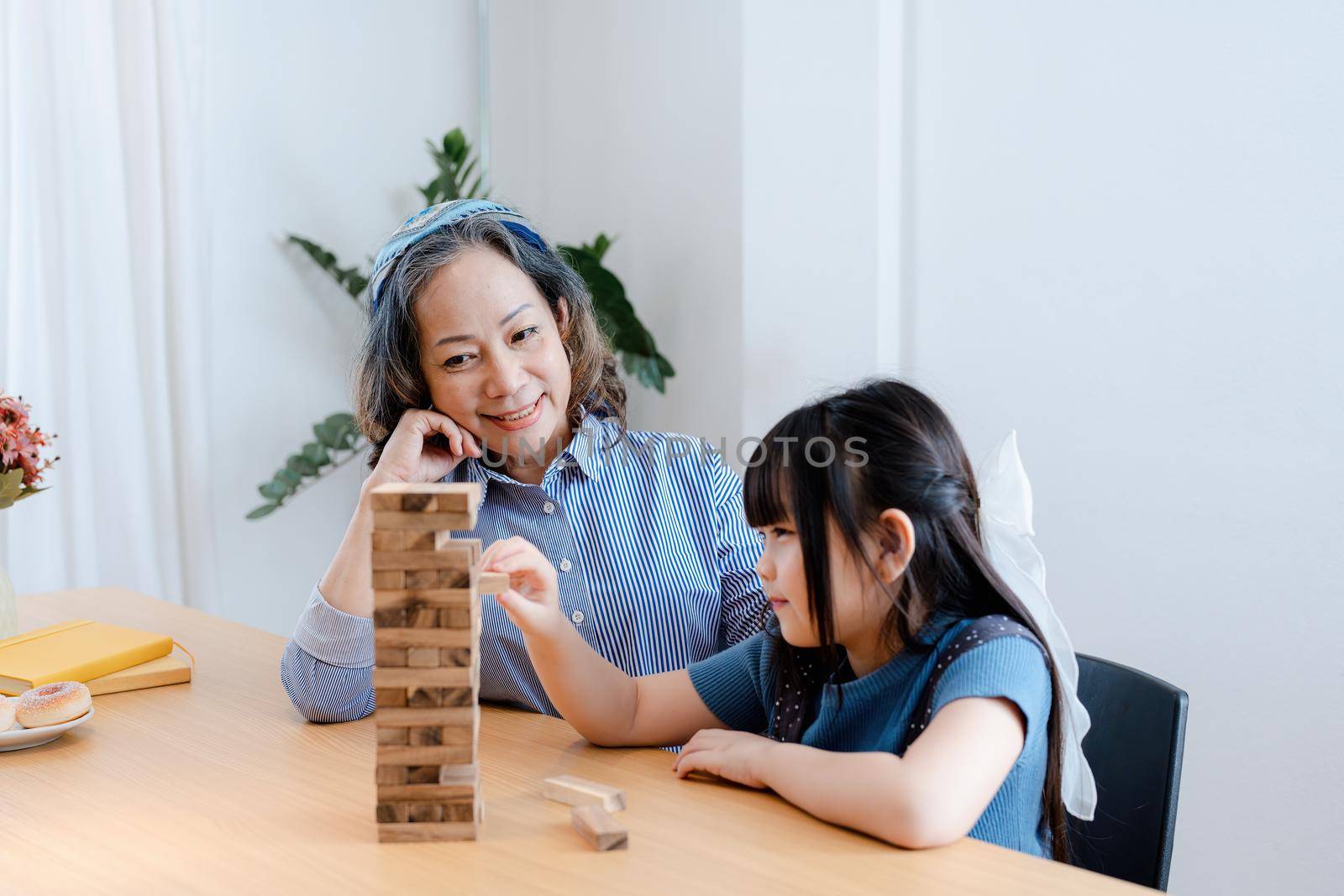 Asian portrait, grandchild granddaughter grandma grandmother and granddaughter happily join in activities to Block wood game Puzzle and enhance skills for grandchildren.