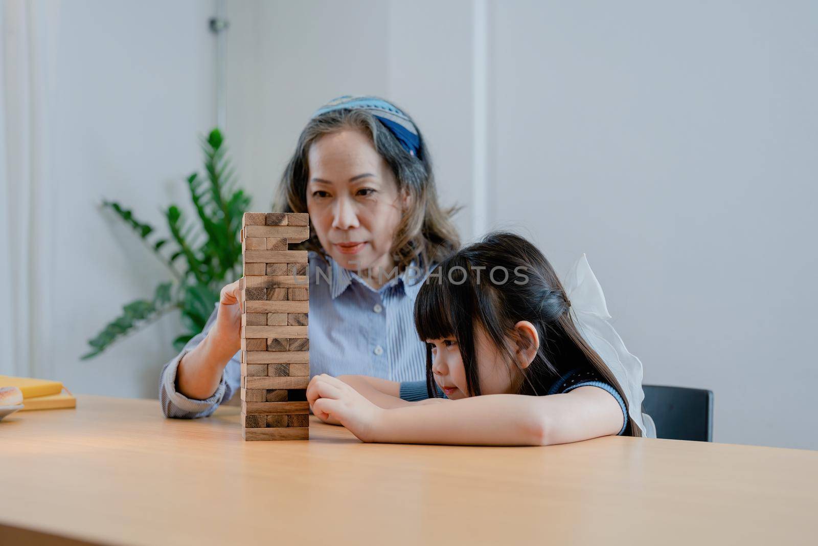 Asian portrait, grandchild granddaughter grandma grandmother and granddaughter happily join in activities to Block wood game Puzzle and enhance skills for grandchildren.