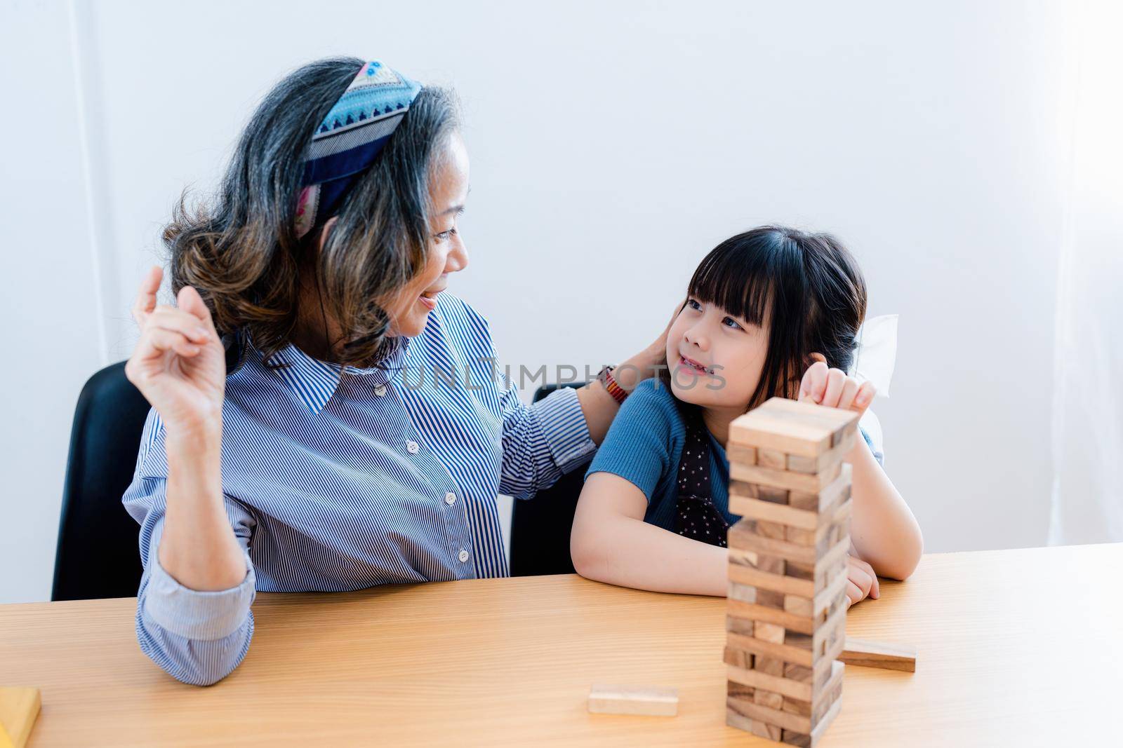 Asian portrait, grandchild granddaughter grandma grandmother and granddaughter happily join in activities to Block wood game Puzzle and enhance skills for grandchildren.