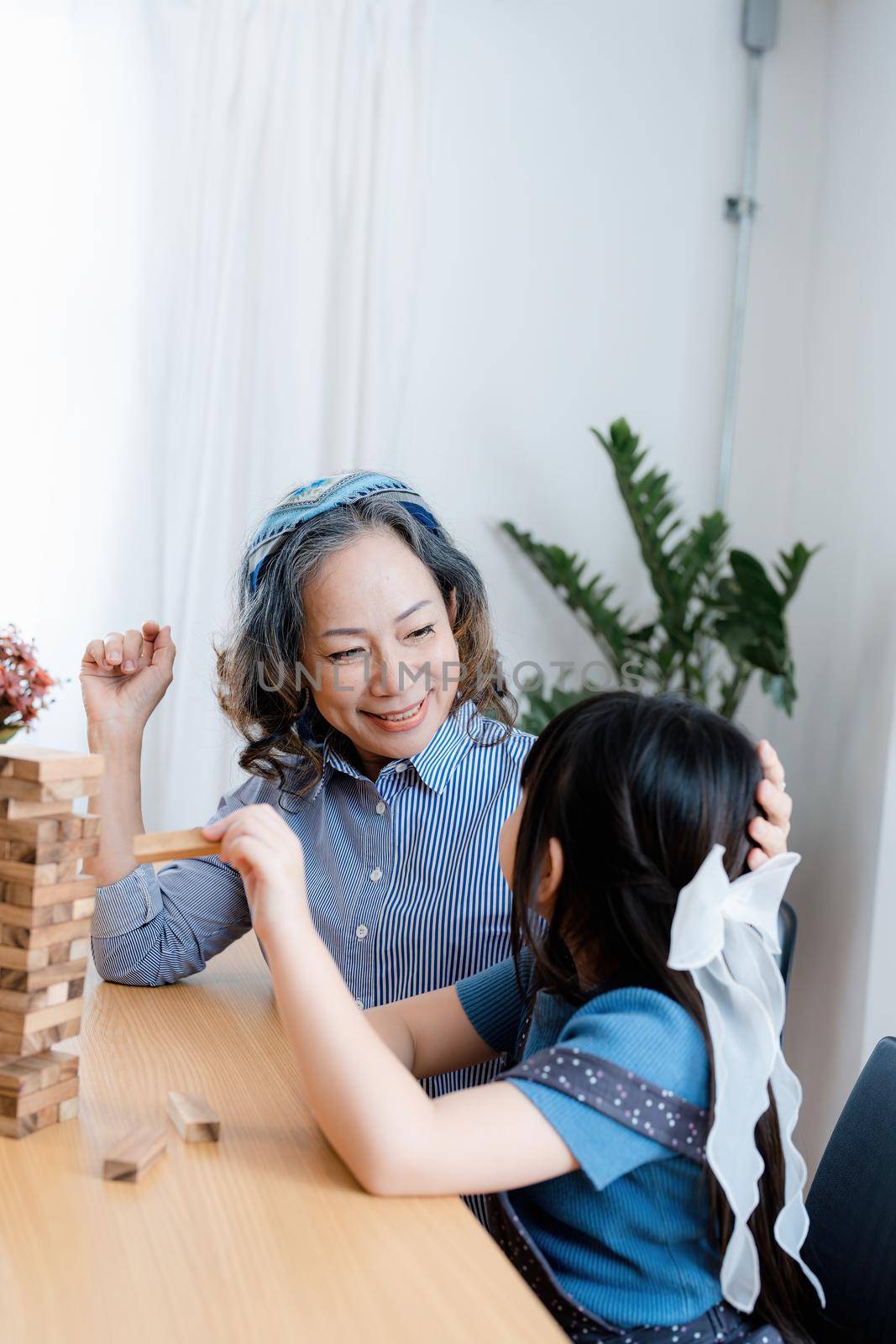 Asian portrait, grandchild granddaughter grandma grandmother and granddaughter happily join in activities to Block wood game Puzzle and enhance skills for grandchildren.