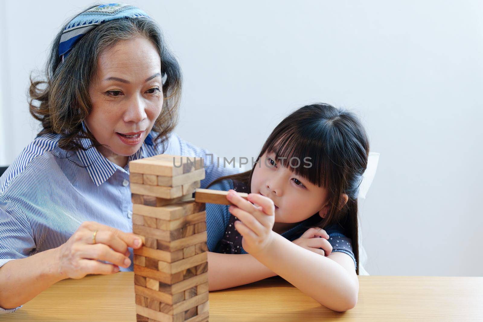 Asian portrait, grandchild granddaughter grandma grandmother and granddaughter happily join in activities to Block wood game Puzzle and enhance skills for grandchildren.