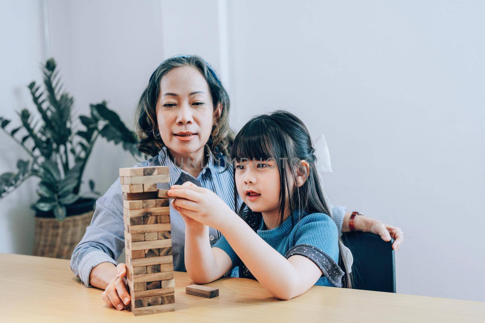 Asian portrait, grandchild granddaughter grandma grandmother and granddaughter happily join in activities to Block wood game Puzzle and enhance skills for grandchildren.