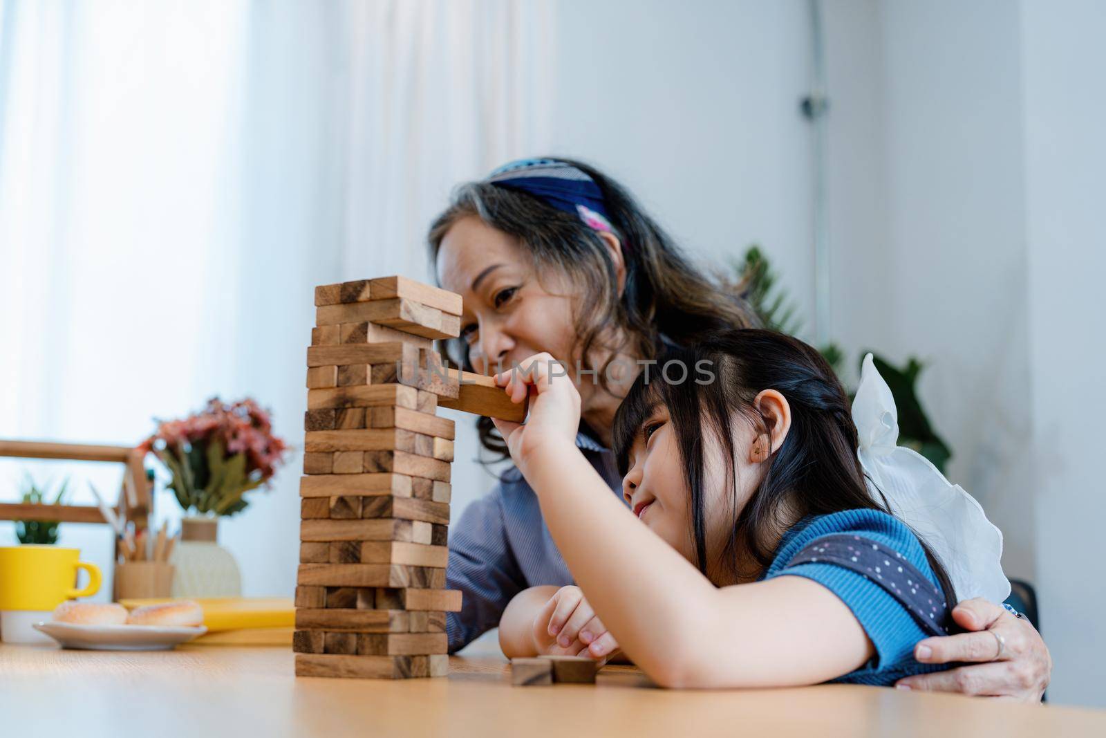 Asian portrait, grandchild granddaughter grandma grandmother and granddaughter happily join in activities to Block wood game Puzzle and enhance skills for grandchildren.