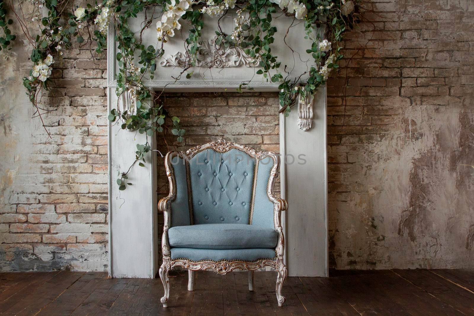 Old antique armchair furniture against a light gray grunge wall, stucco, and vines with flowers Abstract empty room.