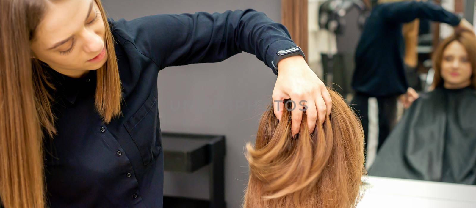 Hairdresser checks hairstyle of woman by okskukuruza