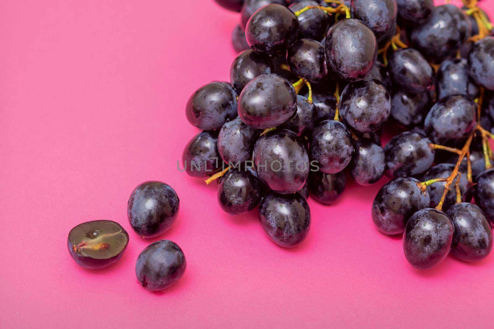 Top view bunch of ripe fresh black grape berry on pink surface