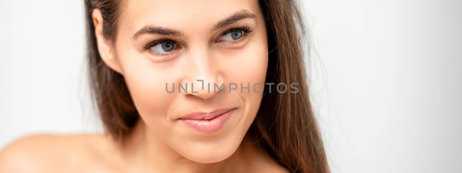 Face portrait of young caucasian woman with naked shoulders and natural make up on white background