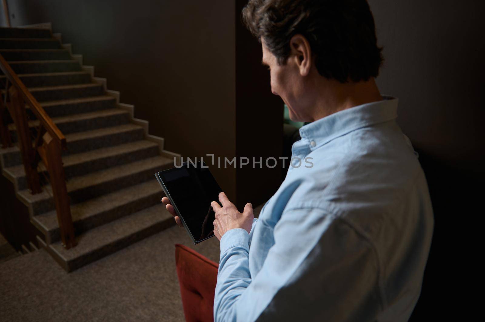 Detail: Hand of a sales manager on a blank black screen of a tablet with copy ad space for advertising text. Rear view of a businessman, entrepreneur, retail assistant using digital gadget in office