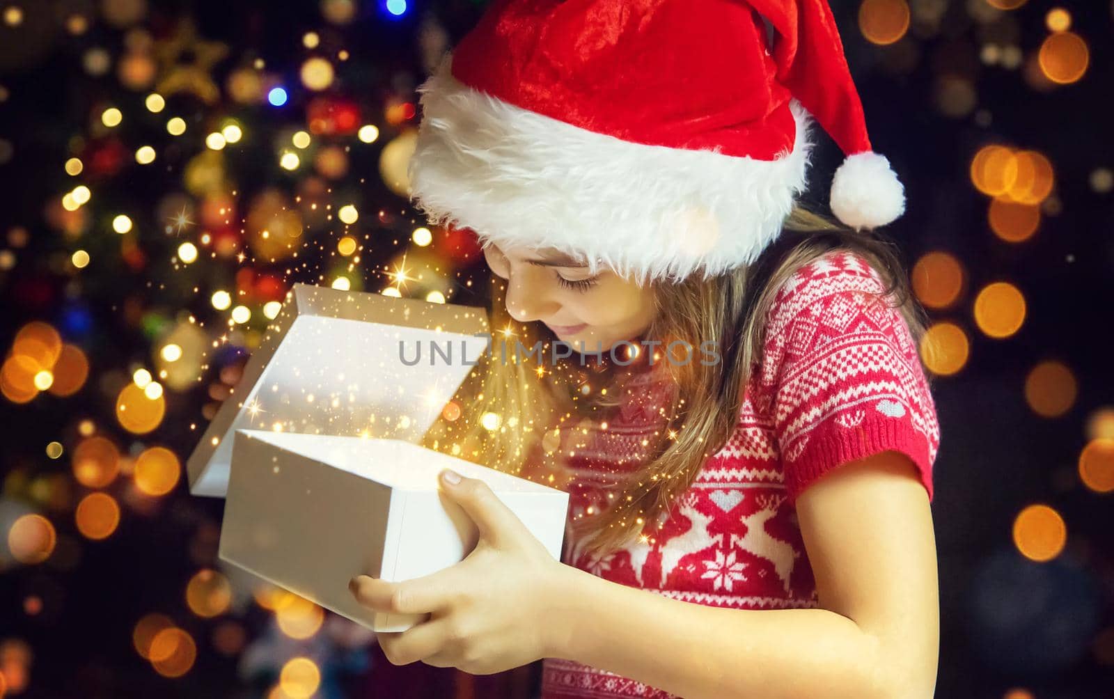 Child opens gifts under the Christmas tree. Selective focus. Holiday.