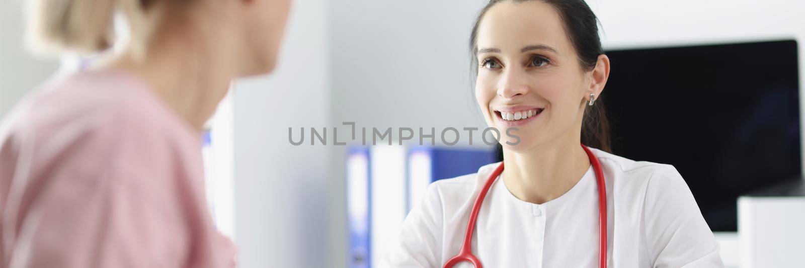 Portrait of smiling doctor measuring patients blood pressure with tonometer tool and talk. Planned checkup at family doctor. Medicine, healthcare concept