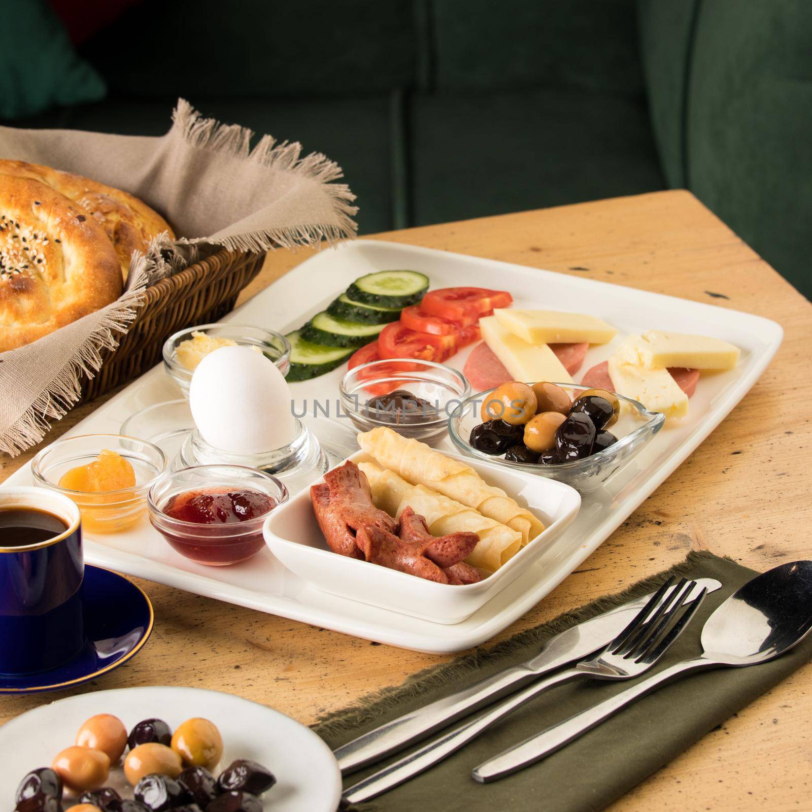 A breakfast plate and a basket of bread on a wooden table