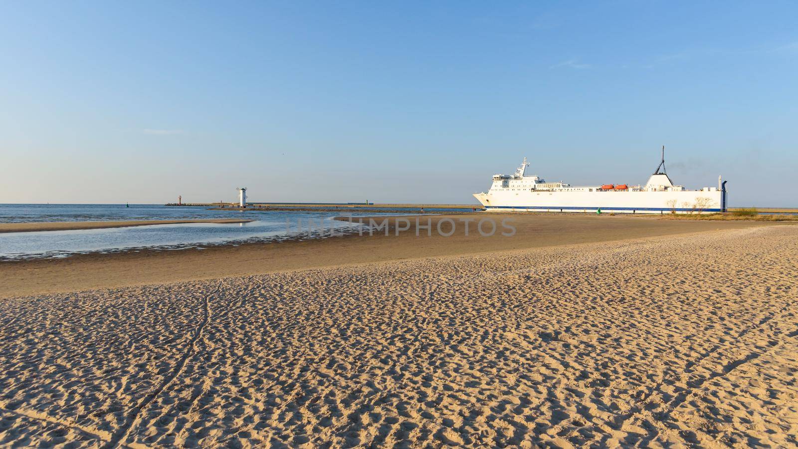 View from the sandy beach of big ferry leaving port of Swinoujscie